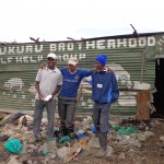 Officials of the Mukuru Brotherhood outside of their pig project structure. Photo credit: Elaine Jones.